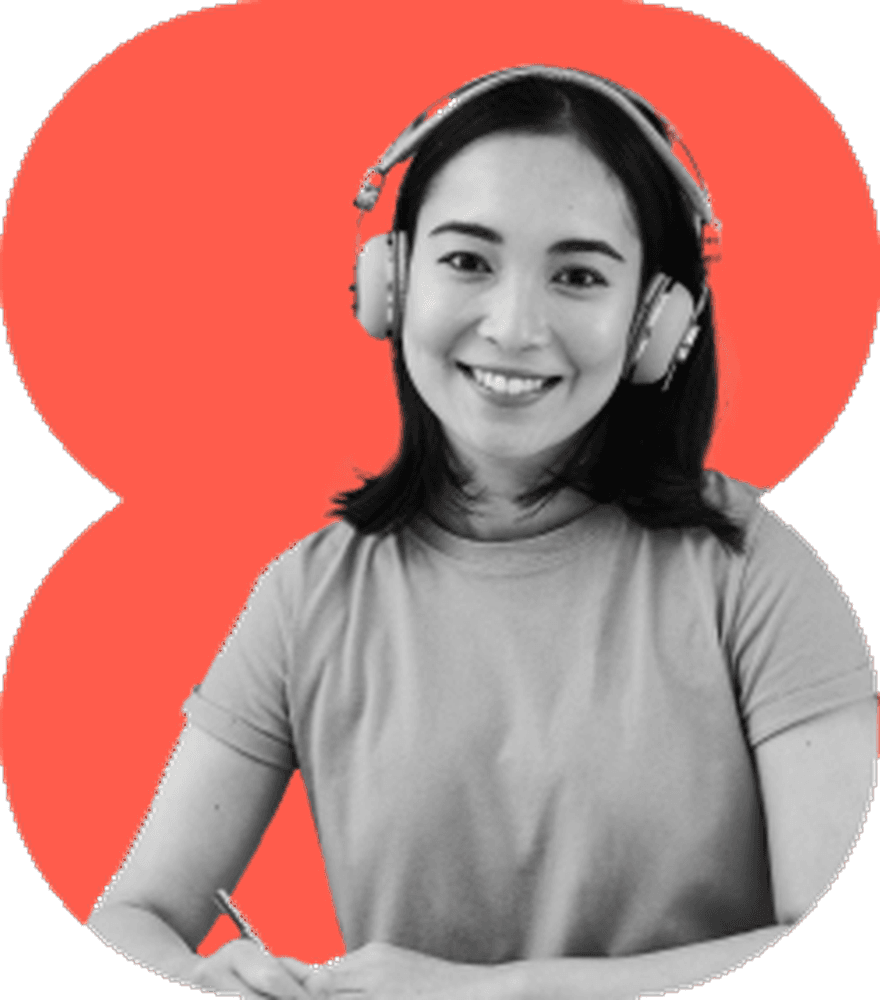 Asian female student with studio over-ear headphones smiling warmly popping out of wide crimson red 4-bulb peanut clover